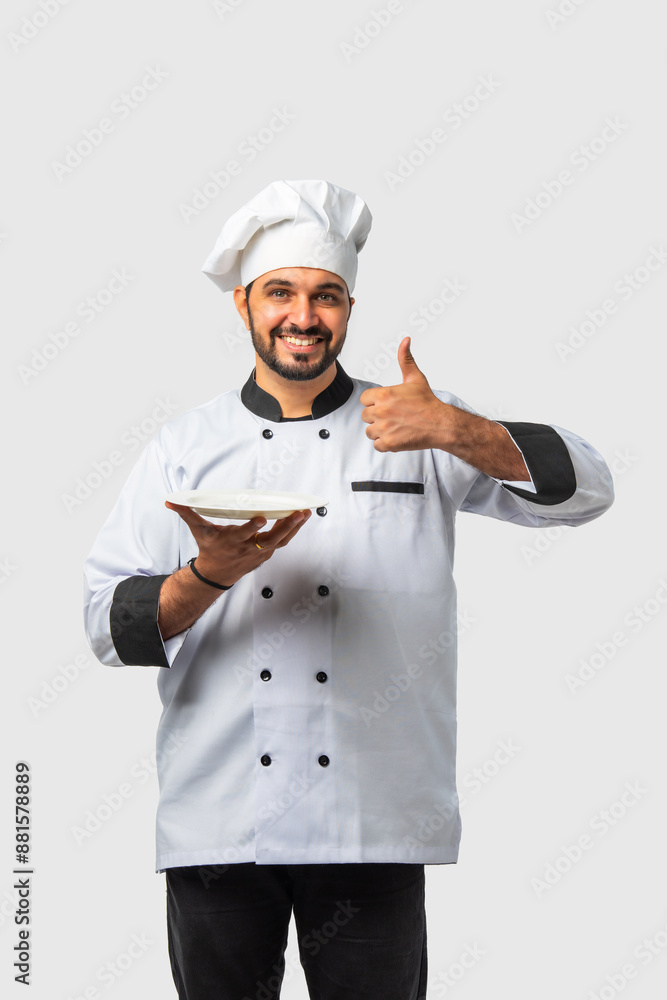 Indian asian young Chef in uniform happily presenting empty white ceramic plate on white background Indian asian young Chef in uniform happily presenting empty white ceramic plate on white background