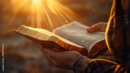 hands hold an open Bible, the sun's rays fall on the Bible. photo