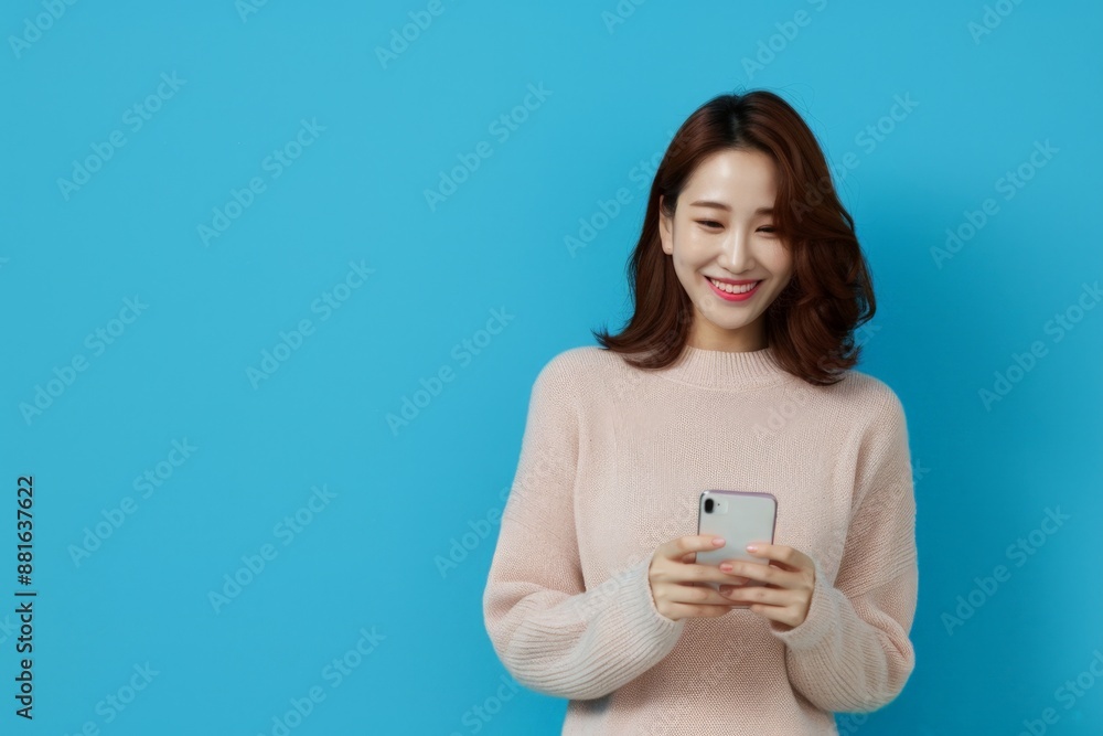 Smiling Young Woman in Pink Sweater Using Smartphone Against Blue Background. Horizontal banner with copy space Smiling Young Woman in Pink Sweater Using Smartphone Against Blue Background. Horizontal banner with copy space