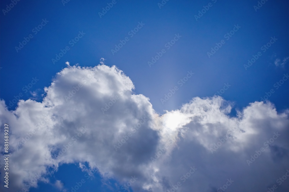 White clouds cover the sun against a blue sky. White clouds cover the sun against a blue sky.