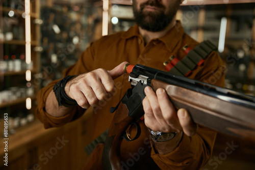 Man loading bullet into the rifle closeup at legal commercial weapon store for hunting hobby photo