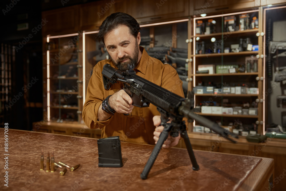 Confident male customer testing new model of automatic rifle in weapon ...
