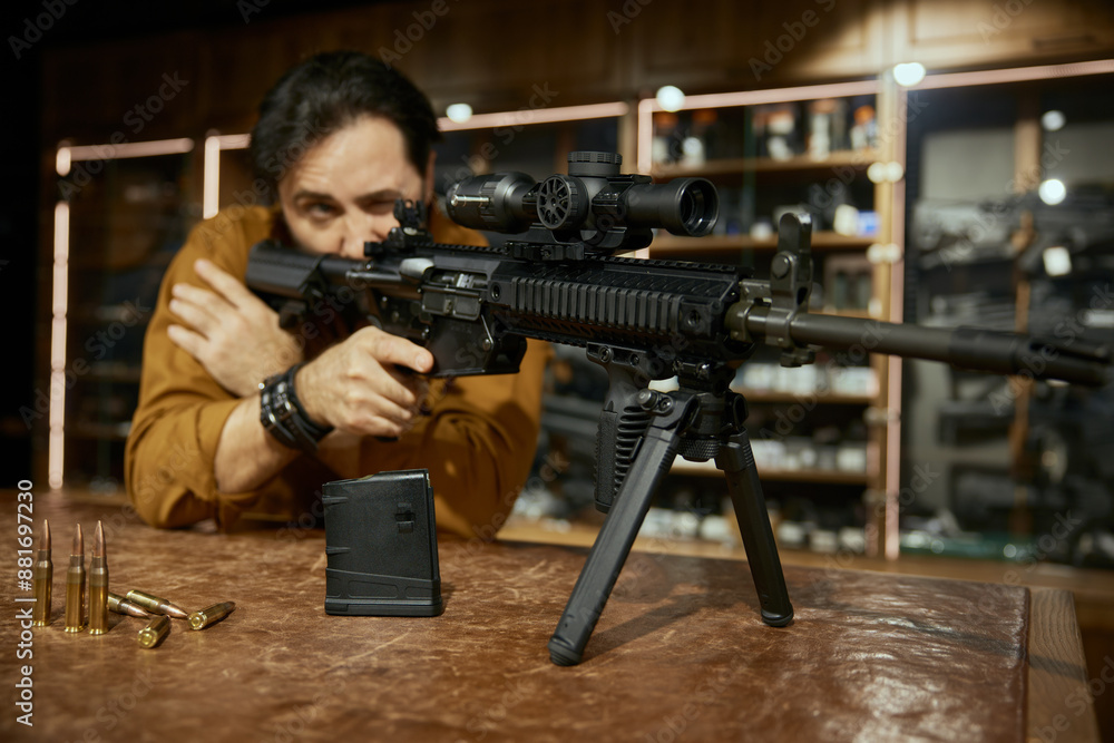 Male customer testing new model of automatic rifle in weapon store ...