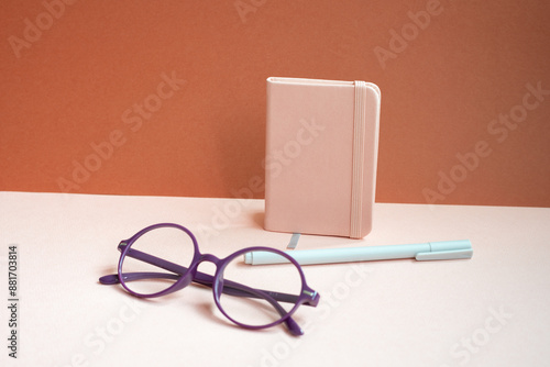 Obraz na płótnie Diary notebook, pen, eyeglasses on pink desk. red background w salonie