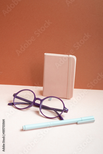 Obraz na płótnie Diary notebook, pen, eyeglasses on pink desk. red background w salonie