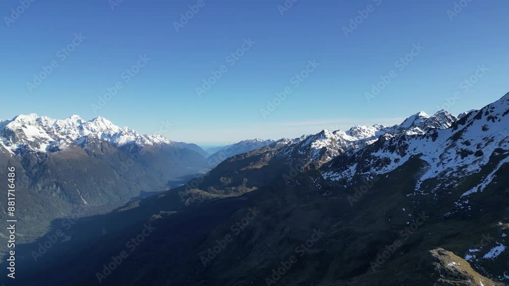 Snow-capped mountains under a clear sky along the Routeburn Track in Fiordland, New Zealand. Snow-capped mountains under a clear sky along the Routeburn Track in Fiordland, New Zealand.