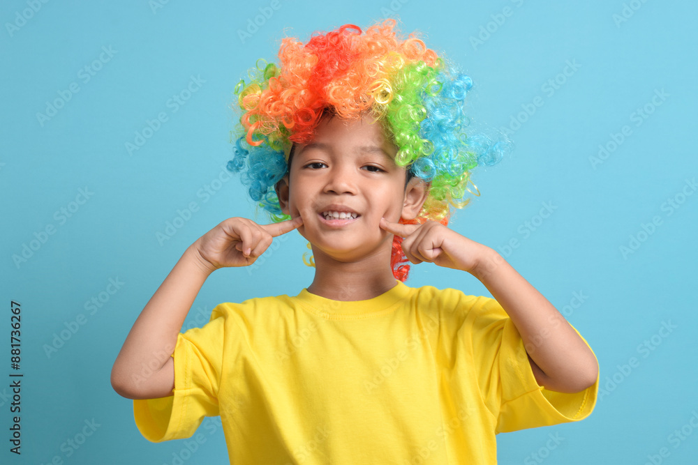Cute little asian boy in clown wig isolated on blue background. copy space Cute little asian boy in clown wig isolated on blue background. copy space