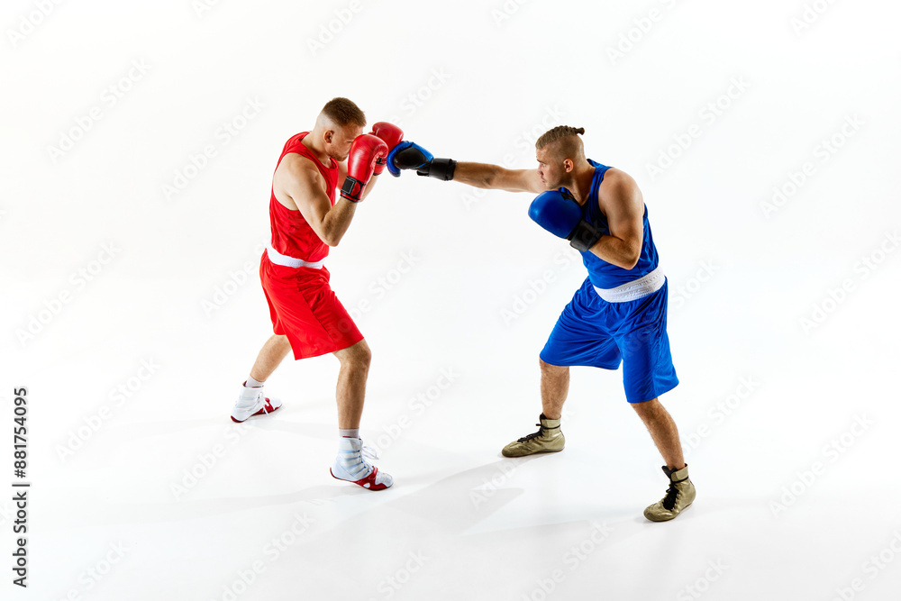 Two boxers engaged in match. One in red gear and other in blue, as they practice their combat skills against white studio background. Concept of professional combat sport, competition. Ad Two boxers engaged in match. One in red gear and other in blue, as they practice their combat skills against white studio background. Concept of professional combat sport, competition. Ad