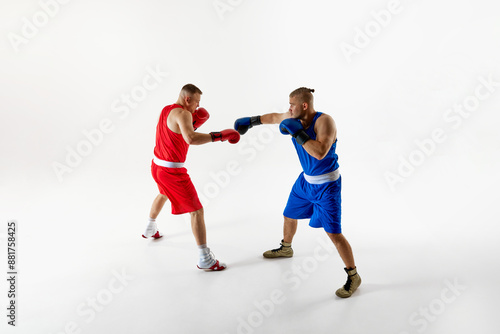 Two determined boxers in blue and red attire in action refining their techniques during intense training session against white studio background. Concept of professional sport, competition. Ad © Lustre Art Group 