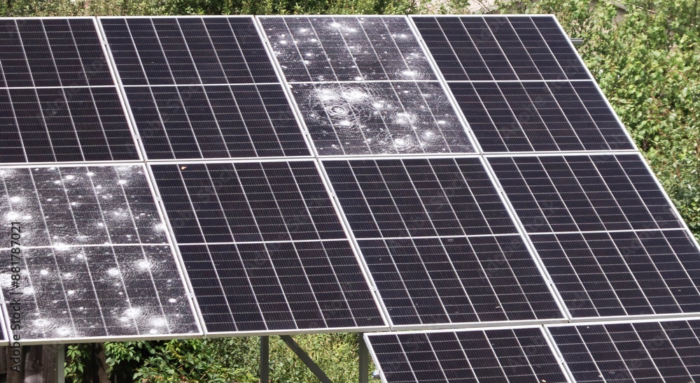 Storm-damaged solar panels in a grid showing visible damage affecting efficiency in an industrial outdoor setting with greenery Storm-damaged solar panels in a grid showing visible damage affecting efficiency in an industrial outdoor setting with greenery