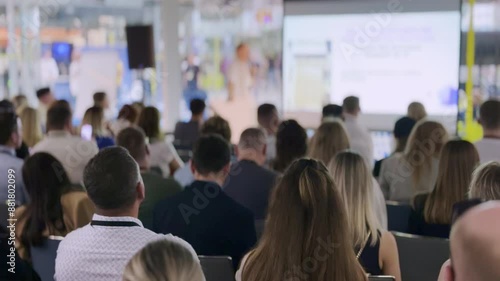Group of people listening to a presentation during a business seminar or conference in a spacious room.