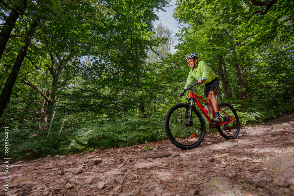 Cyclist teen enjoying ride through a scenic, lush green forest Cyclist teen enjoying ride through a scenic, lush green forest