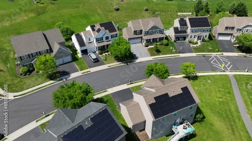 Solar panels on residential home rooftops in USA neighborhood. Modern middle class houses with renewable, self-sufficient power supply. Aerial tilt up reveal.