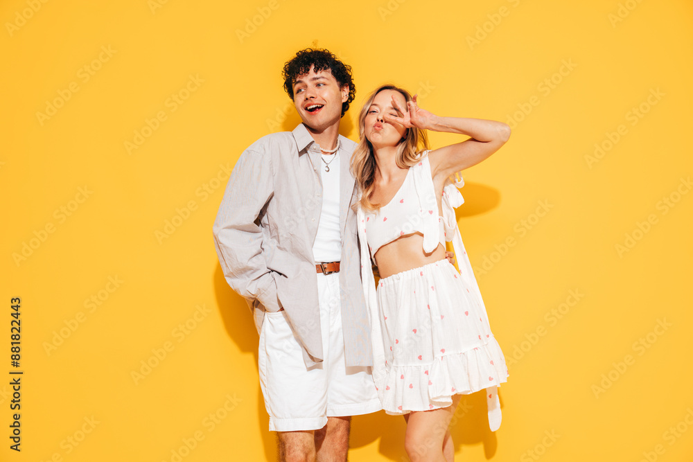 Happy beautiful romantic teenage couple. Smiling handsome caucasian man and young woman in summer clothes posing in studio, hugging sharing positive emotions, cheerful and happy. Isolated on yellow Happy beautiful romantic teenage couple. Smiling handsome caucasian man and young woman in summer clothes posing in studio, hugging sharing positive emotions, cheerful and happy. Isolated on yellow