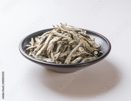 Close-up of stacked dried anchovy on black jar bowl and white floor, South Korea 