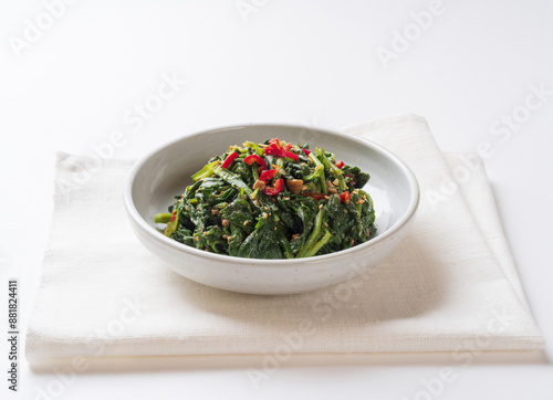 Close-up of seasoned Chwinamul with mince and red pepper on dish and cloth, South Korea 