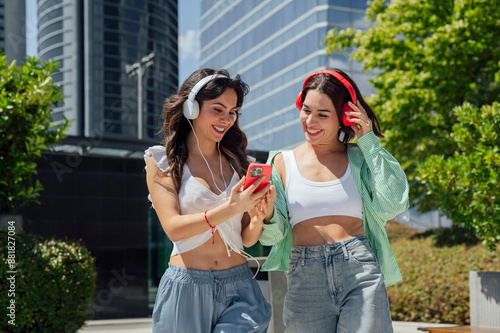 Two friends listening to music on the mobile phone on the street