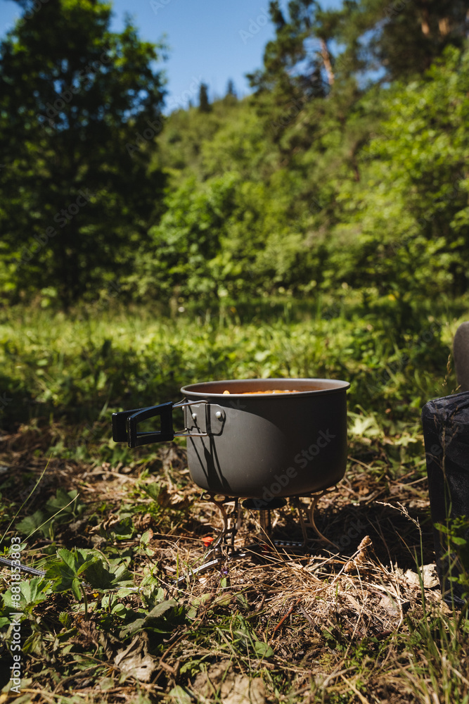 In the vast open field, a pot sits on a stove surrounded by trees, plants, grass, and shrubs under the sky, forming a serene and scenic natural landscape with abundant vegetation In the vast open field, a pot sits on a stove surrounded by trees, plants, grass, and shrubs under the sky, forming a serene and scenic natural landscape with abundant vegetation
