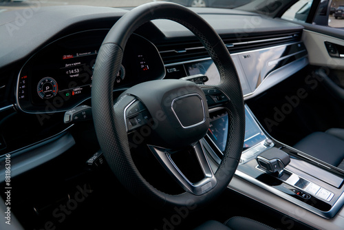 View of the driver's seat of the car through the window. Visible steering wheel, speedometer, gear knob