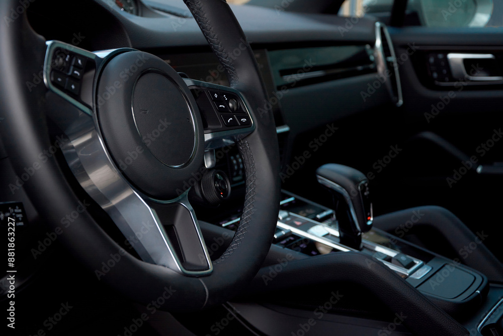 The view of the dark dashboard from the driver's seat is shown, with a close-up of the steering wheel in the foreground. The interior of the car is dark, with metal accents The view of the dark dashboard from the driver's seat is shown, with a close-up of the steering wheel in the foreground. The interior of the car is dark, with metal accents