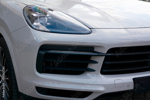 Grey car bumper with black accents, headlight and wheel.