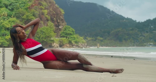 The tropical island of Trinidad has a young girl in a bikini laying on its beach. photo