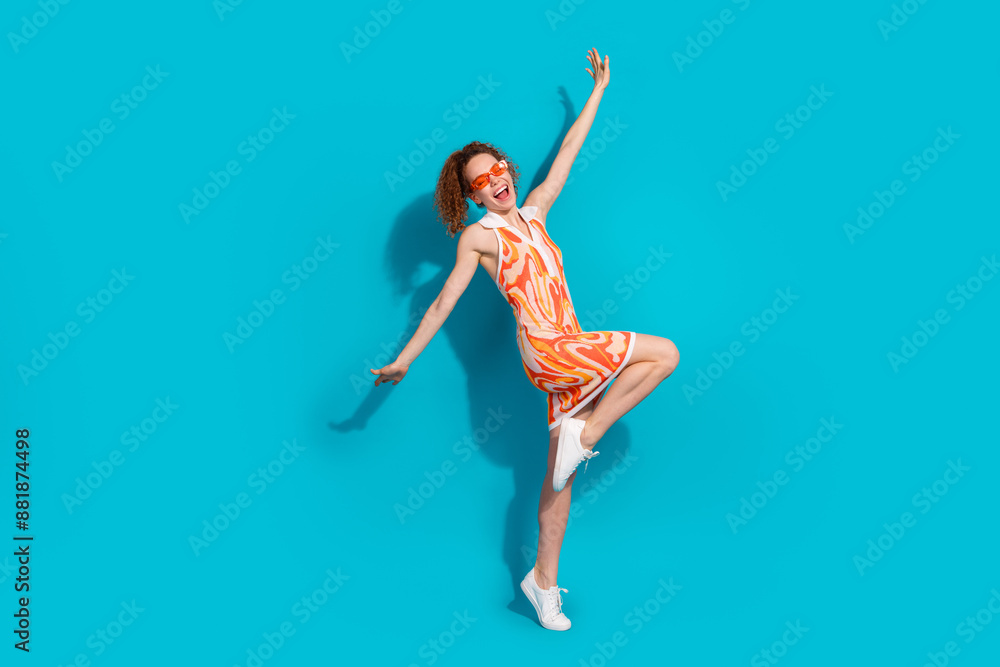 Fototapeta premium Full size photo of pretty young girl sunglass dance spread hands fly wear trendy orange outfit isolated on aquamarine color background