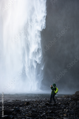 Obraz na płótnie Stunning view of the Skógafoss Waterfall with a tourist taking pictures. Skógafoss is one of the biggest waterfalls in Iceland, situated on the Skoga River in the south of Iceland. w salonie