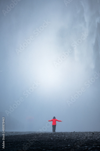Obraz na płótnie Stunning view of the Skógafoss Waterfall with a tourist wearing a red jacket. Skógafoss is one of the biggest waterfalls in Iceland, situated on the Skoga River in the south of Iceland. w salonie