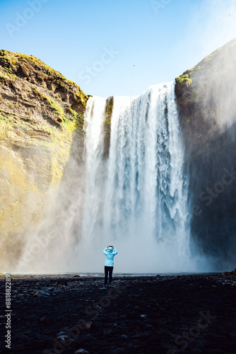 Obraz na płótnie Stunning view of the Skógafoss Waterfall with a tourist taking pictures. Skógafoss is one of the biggest waterfalls in Iceland, situated on the Skoga River in the south of Iceland. w salonie