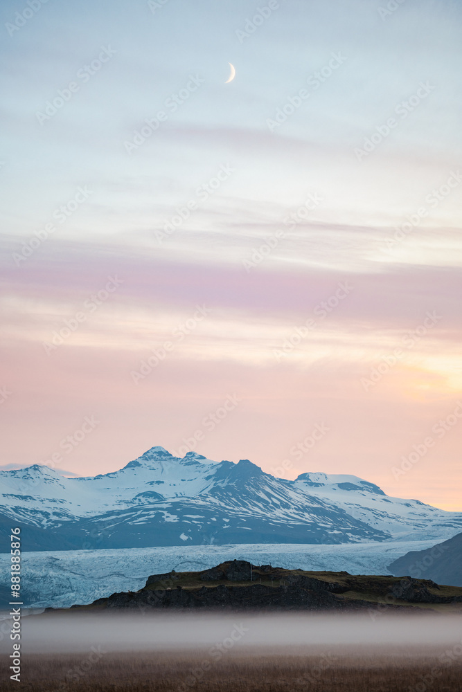 Stunning view of a dramatic landscape with some snowy mountains and a glacier in the distance during a beautiful sunrise, Iceland.