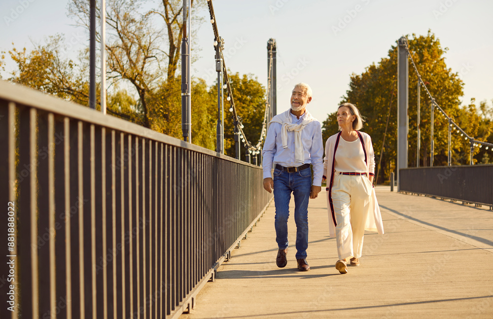 Joyful senior couple, smiling and happy, takes a leisurely stroll in a city park, enjoying vacation or holiday together. They spend quality time on date, cherishing each other company during walking. Joyful senior couple, smiling and happy, takes a leisurely stroll in a city park, enjoying vacation or holiday together. They spend quality time on date, cherishing each other company during walking.