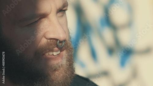 Wallpaper Mural close-up shot of a young man with curly brown hair and a beard, removing his sunglasses. His proud expression conveys confidence and self-assurance. Torontodigital.ca