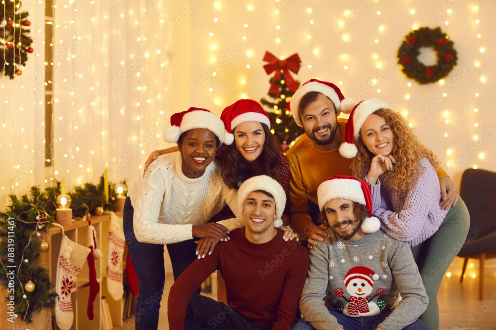 Group portrait of smiling multiethnic friends in Santa hats pose together for New Year picture. Happy diverse international young people celebrate Christmas in decorated home. Winter holidays. Group portrait of smiling multiethnic friends in Santa hats pose together for New Year picture. Happy diverse international young people celebrate Christmas in decorated home. Winter holidays.