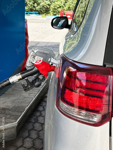 Refueling a silver car with a red gasoline pump with 92 octane at a gas station photo