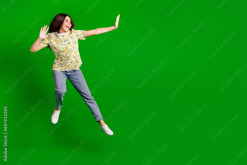 Full size photo of pretty teen girl jump playful wear trendy flowers print outfit isolated on green color background Full size photo of pretty teen girl jump playful wear trendy flowers print outfit isolated on green color background