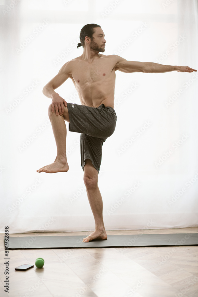 Fototapeta premium Handsome man practices yoga on a mat at home.