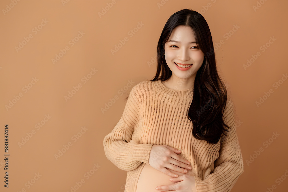 Obraz premium Beautiful Asian Pregnancy happiness woman smile in knit shirt touch belly waiting for unborn baby on beige isolated background. Mom holding tummy. Journey to motherhood.