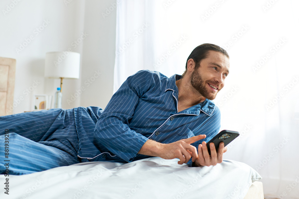 A man peacefully engaged with his cellphone while laying on a comfy bed. A man peacefully engaged with his cellphone while laying on a comfy bed.