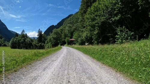Gravel strasse in einem Tal mit grünen Wiesen und blauem Himmel. E-Bike fahren in der Schweiz