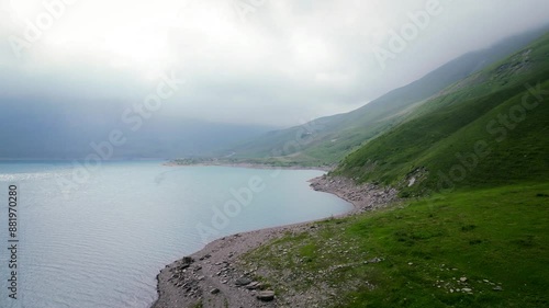 On the shores of Lake Mont Cenis between France and Italy, 4K drone video before sunset, green valley with a foggy atmosphere