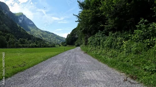 Fahrradtour auf einer Forststrasse mit grünen Wiesen und blauem Himmel in einem Tal in der Schweiz