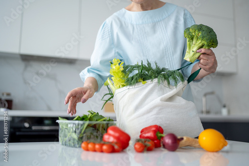 Photography In a contemporary kitchen, a woman is unloading fresh groceries using ecofriendl