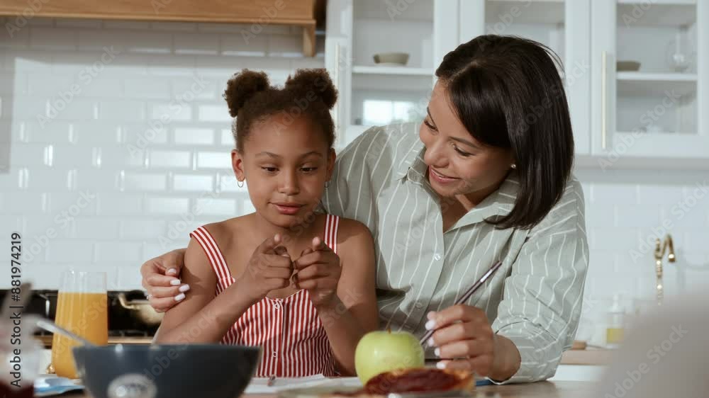 African American woman and little daughter talking joyfully during breakfast in the morning. Black girl and her mother sitting at kitchen table and drawing together at home. Family bonding. African American woman and little daughter talking joyfully during breakfast in the morning. Black girl and her mother sitting at kitchen table and drawing together at home. Family bonding.