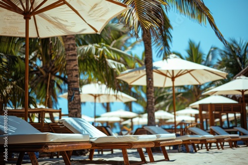 A serene beach scene featuring sun loungers with white umbrellas arranged under tall palm trees, creating a perfect environment for relaxation and enjoyment at a resort. © Milos