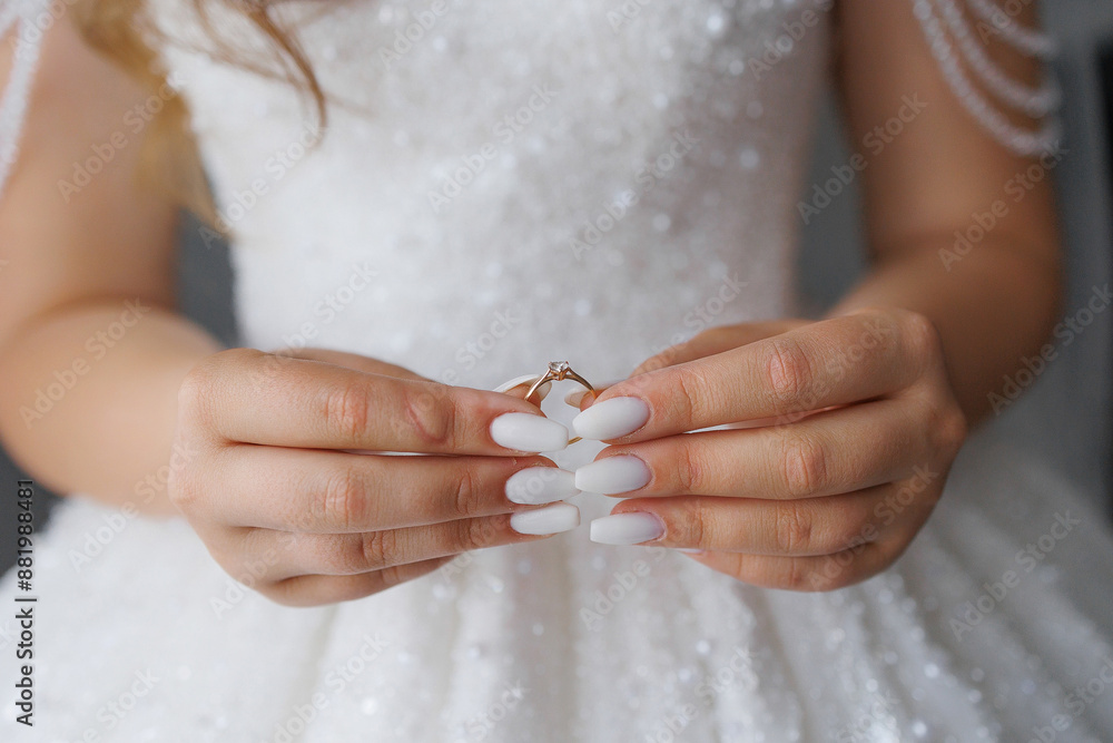 A woman is holding a ring in her hand. The ring is gold and has a diamond on it. The woman is wearing a white dress and has long blonde hair. Concept of elegance and sophistication A woman is holding a ring in her hand. The ring is gold and has a diamond on it. The woman is wearing a white dress and has long blonde hair. Concept of elegance and sophistication