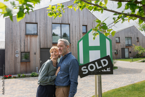 Happy couple outside the property they have just sold photo