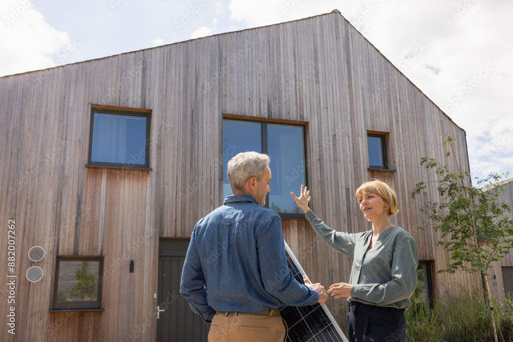 Eco conscious home owner discussing with an engineer installing solar panels Eco conscious home owner discussing with an engineer installing solar panels