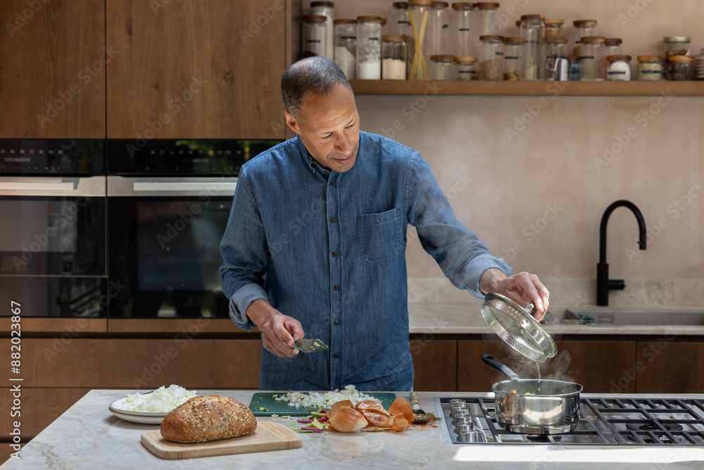 Mature retired male cooking a homemade meal in his kitchen Mature retired male cooking a homemade meal in his kitchen