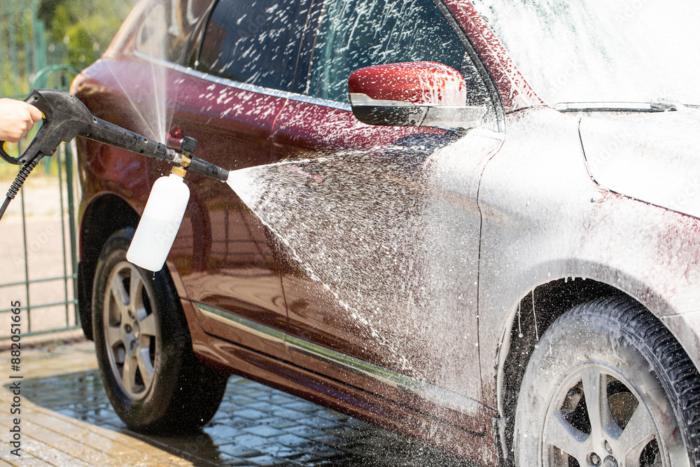 Naklejka premium Cleaning car using active foam. Man washing his car